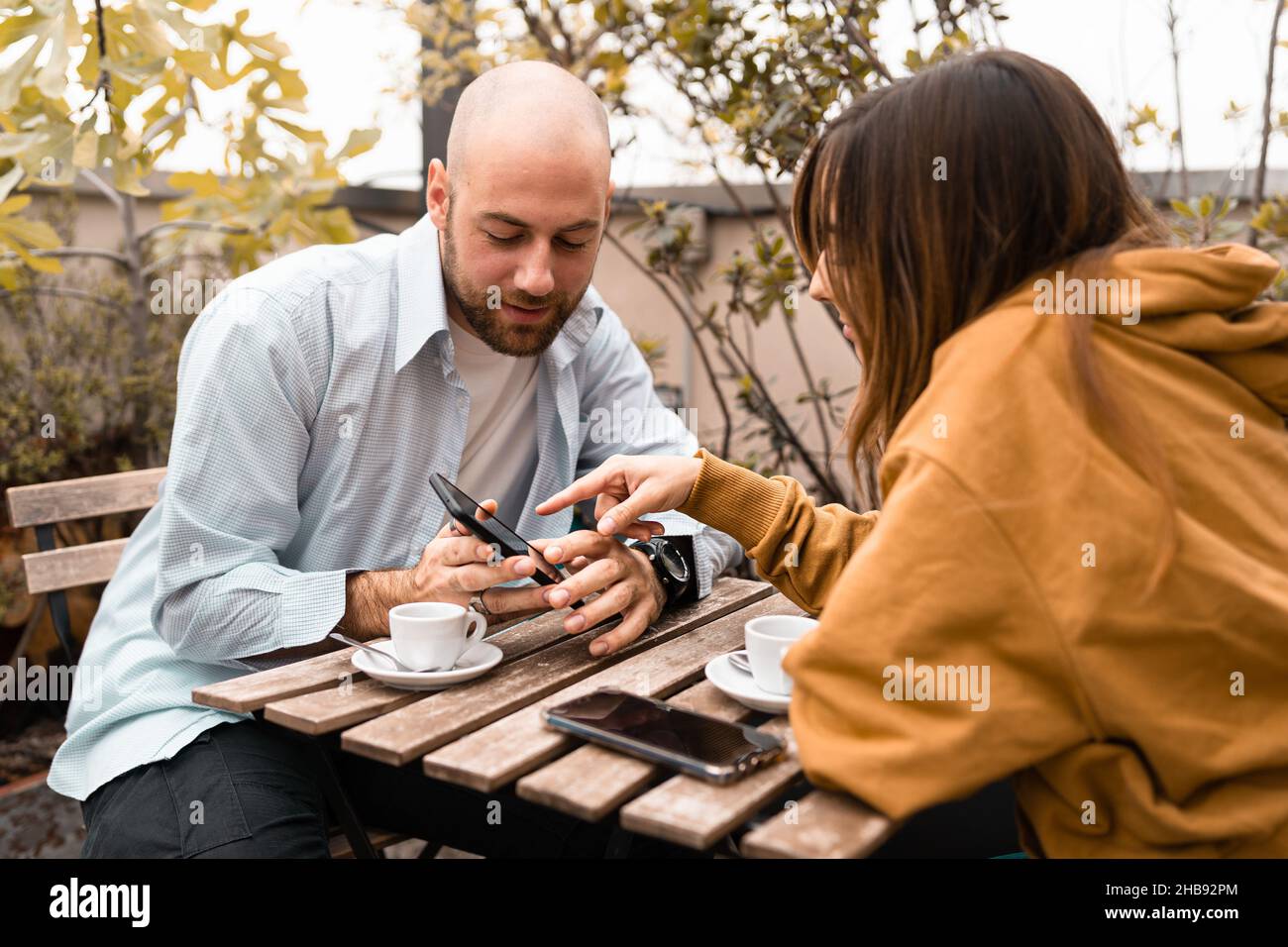 Coppia di giovani che guardano contenuti sullo smartphone seduti all'aperto Foto Stock