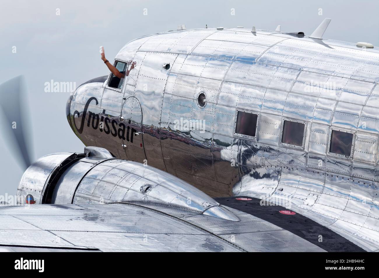 Primo piano di un aereo svizzero Douglas DC-3 Dakota con pilota che sventola fuori dal cockpit. Foto Stock