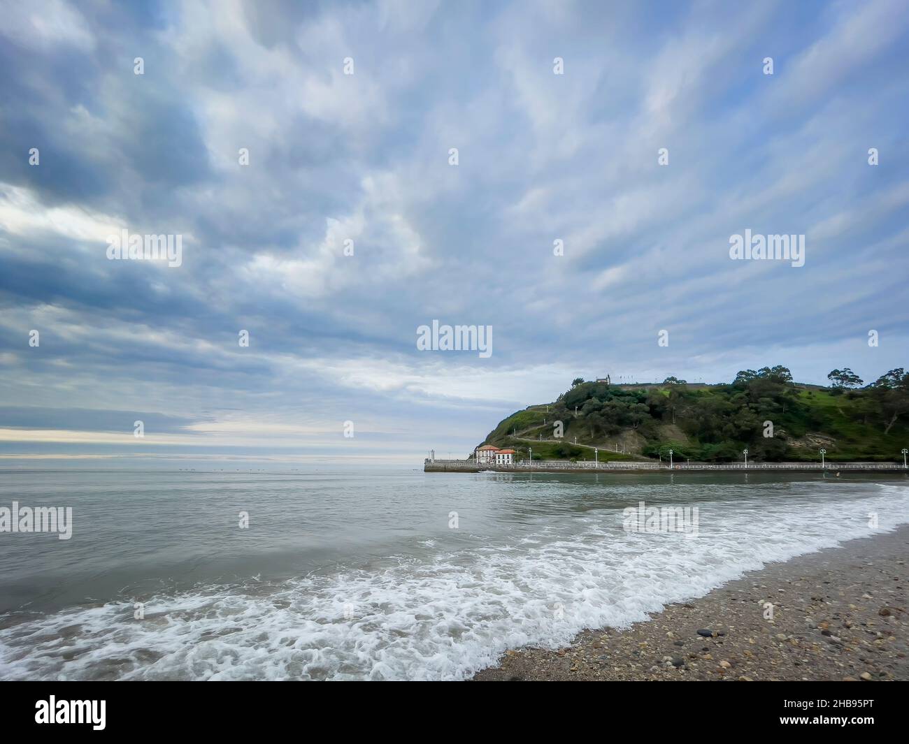 Spiaggia vuota al tramonto con barche all'orizzonte e un faro ad un'estremità della spiaggia, spiaggia di Santa Marina a Ribadesella, Asturias, Spagna, orizzonti Foto Stock