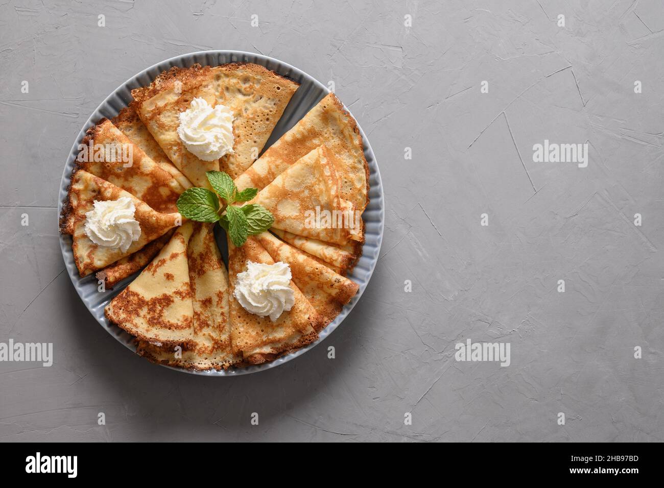 Pancake o blini sottili russi con panna montata su tavola di pietra grigia. Vista dall'alto. Shrovetide. Spazio per il testo. Foto Stock