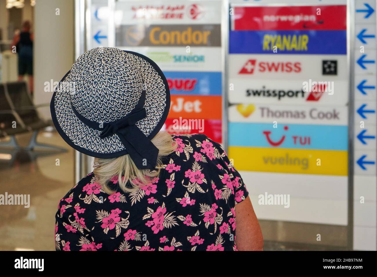 Palma, Spagna - 25 settembre 2019: Vista da dietro - donna anziana sconosciuta con cappello di vacanza in aeroporto, blurred linee aeree loghi in background, closeup d Foto Stock