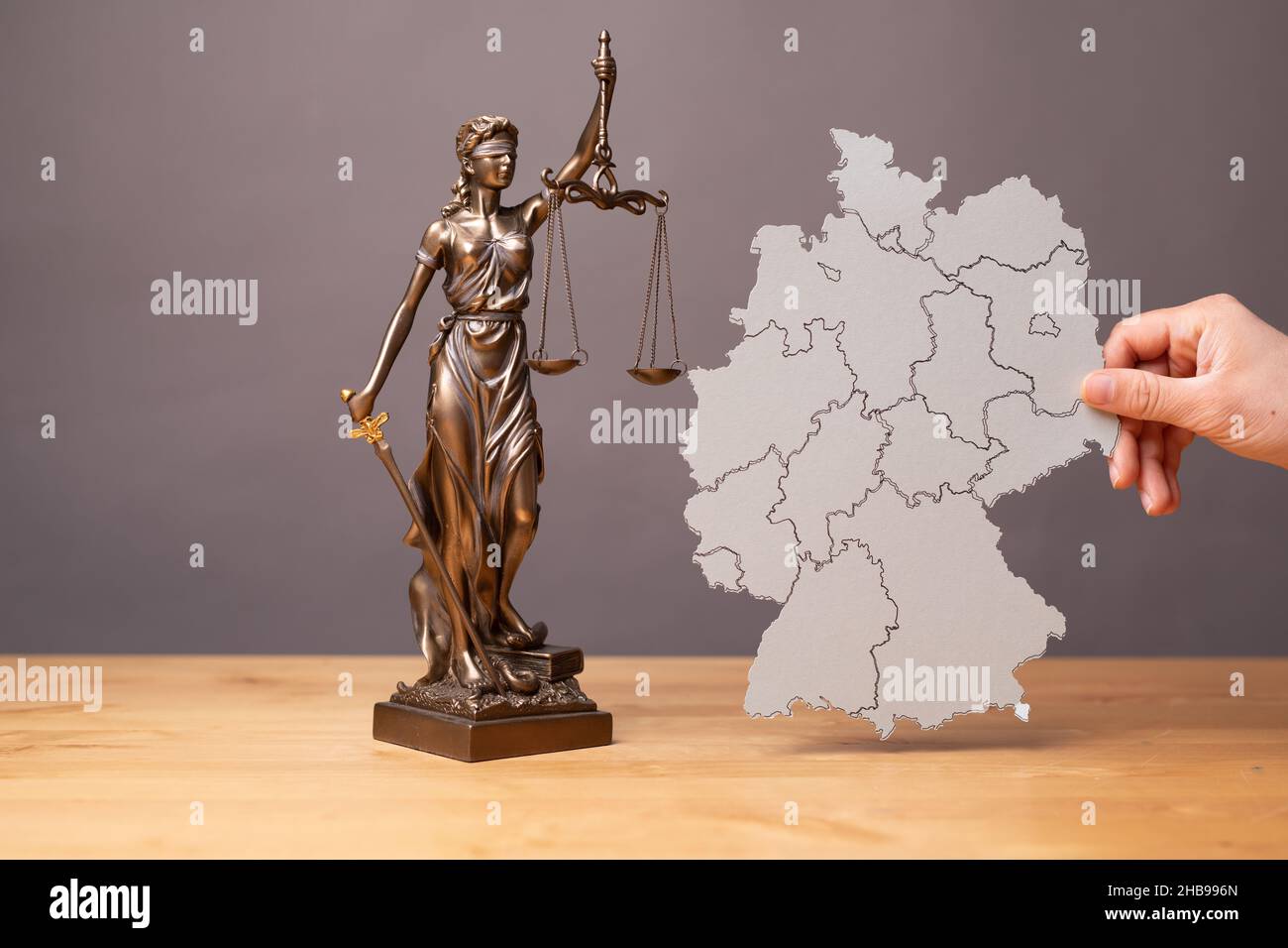 Statua di una donna con scale come simbolo di l su una superficie di legno con una sagoma di una mappa Foto Stock Statua di una donna con scale come simbolo di l su una superficie di legno con una sagoma di una mappa Foto Stock
