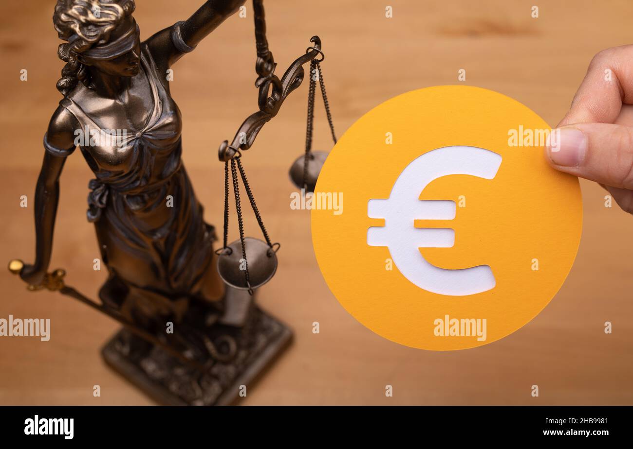 Statua di una donna con le scale come simbolo di diritto e giustizia e l'euro segno su una superficie di legno Foto Stock Statua di una donna con le scale come simbolo di diritto e giustizia e l'euro segno su una superficie di legno Foto Stock