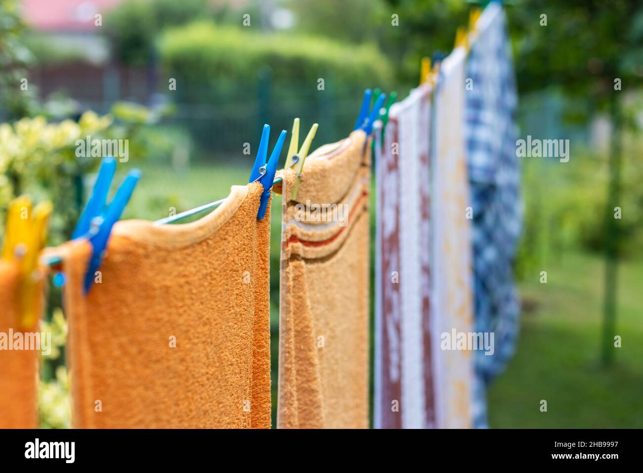 La lavanderia lavata è appesa sugli outddors del clothesline. Focalizzazione selettiva sul pin dei vestiti. Asciugando un asciugamano e un abbigliamento in cotone pulito e umido dopo il lavaggio Foto Stock