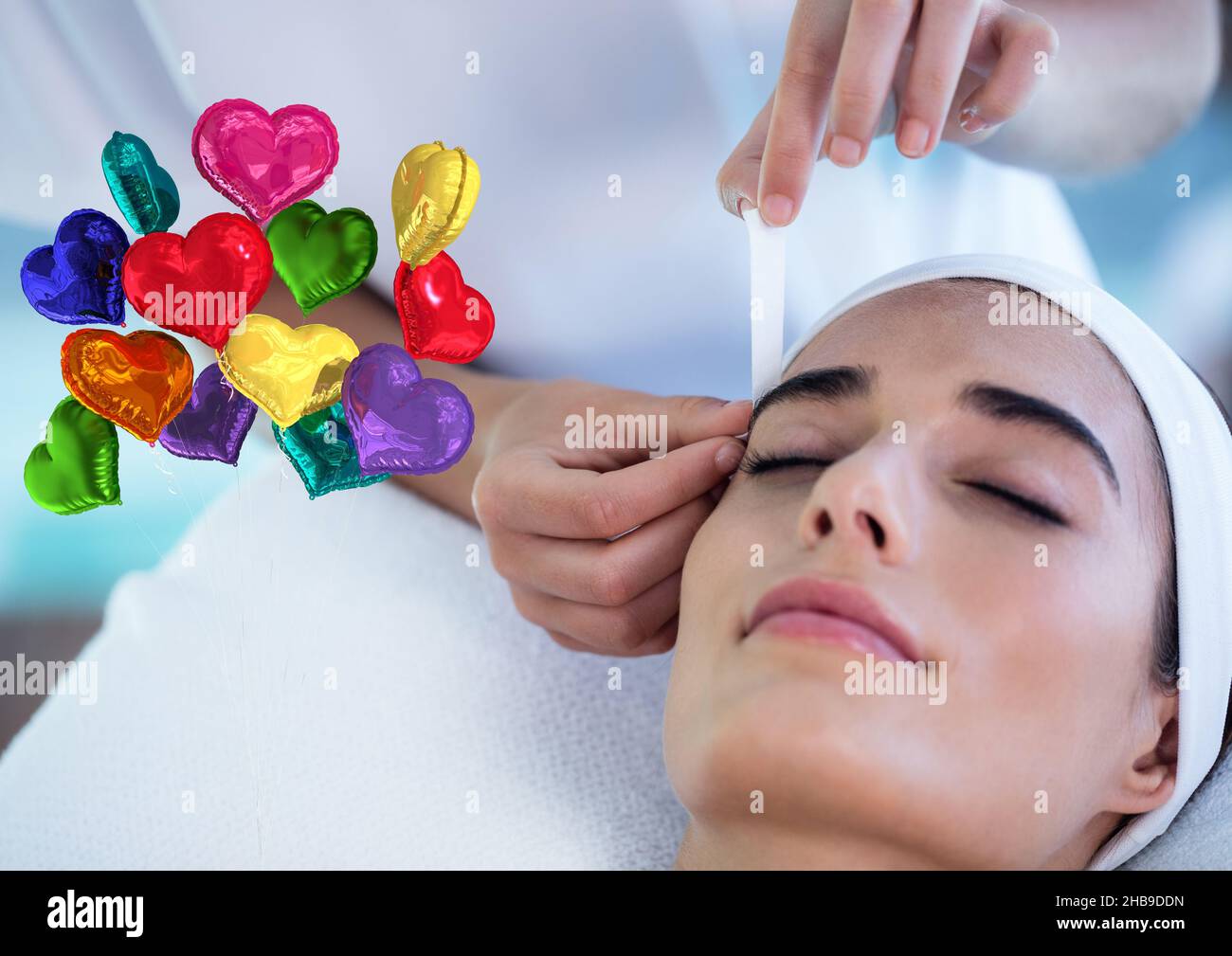 Immagine composita di palloncini colorati a forma di cuore contro la donna che riceve il trattamento viso di bellezza Foto Stock