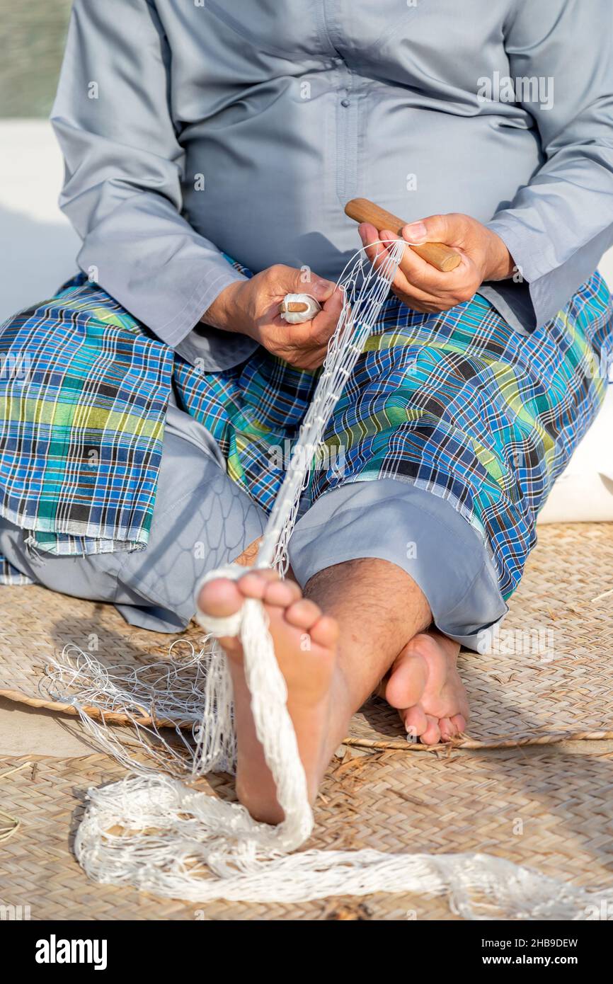 L'uomo vecchio sta maglia rete da pesca tradizionale, mani e piedi in cornice Foto Stock