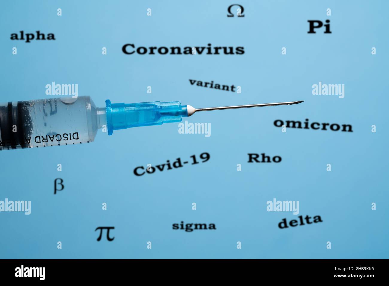 Concetto di efficacia dei vaccini contro il covid-19 con siringa ipodermica di fronte a parole che descrivono il coronavirus Foto Stock