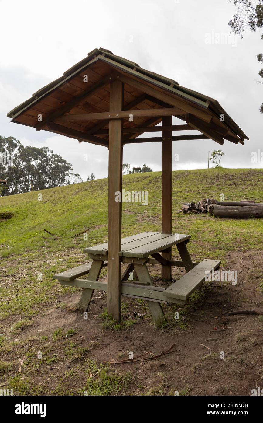 paesaggio di un parco esterno, dettaglio di un tavolo con sgabello e soffitto in legno, mobili rustici in mezzo alla natura, luogo di riposo e barbecue sono Foto Stock