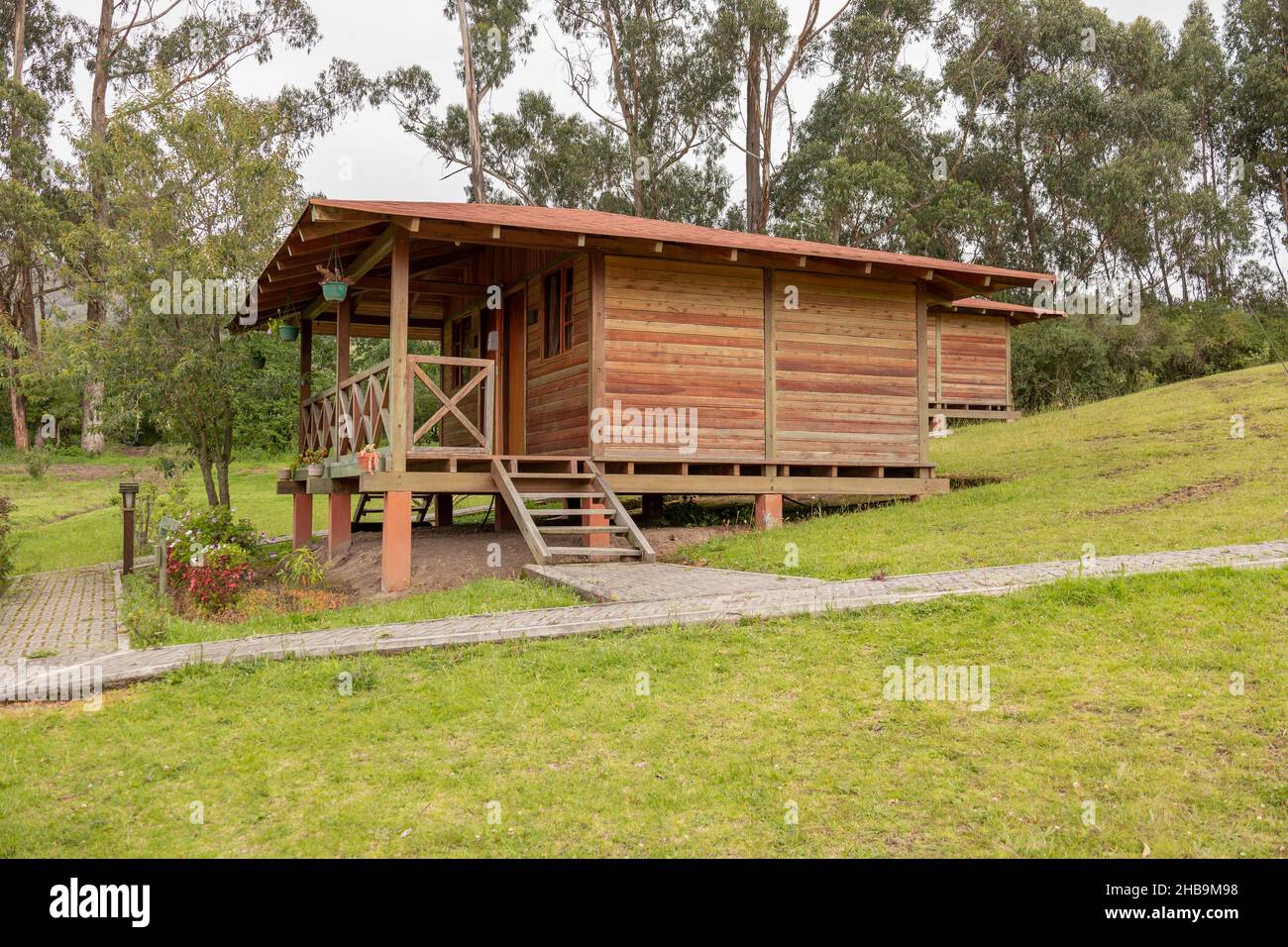 bella facciata di una cabina rustica in campagna circondata dalla natura, struttura in legno con balcone e scalini, stile di vita e turismo in un peacef Foto Stock