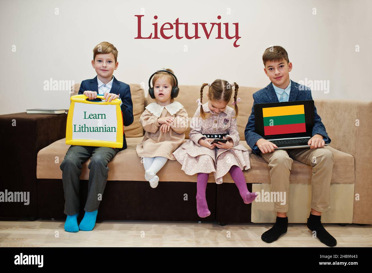 Quattro bambini mostrano iscrizione imparare il lituano. Concetto di apprendimento delle lingue straniere. Foto Stock