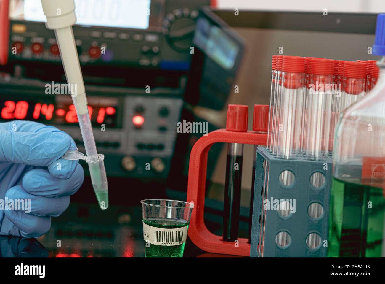 Preparazione del campione per la spettrometria di massa in un laboratorio scientifico. Riempire le provette con campioni con una pipetta e strumenti di misurazione sullo sfondo. Foto Stock