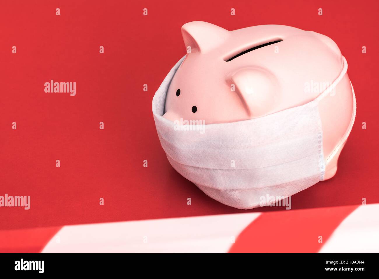 Rosa Piggy Bank si erge su uno sfondo rosso indossando maschera medica, il nastro di divieto rosso e bianco è teso. Coronavirus Cinese , 2019-nCoV Foto Stock