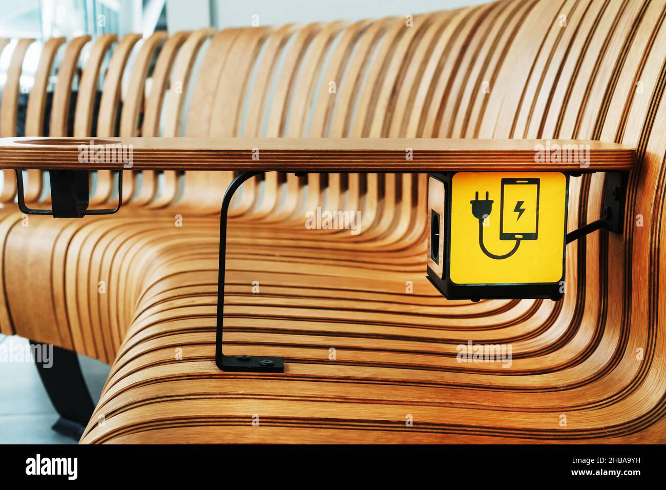 Una presa con un segnale di ricarica del dispositivo su un banco di legno all'aeroporto. USB, Wireless, spina Foto Stock