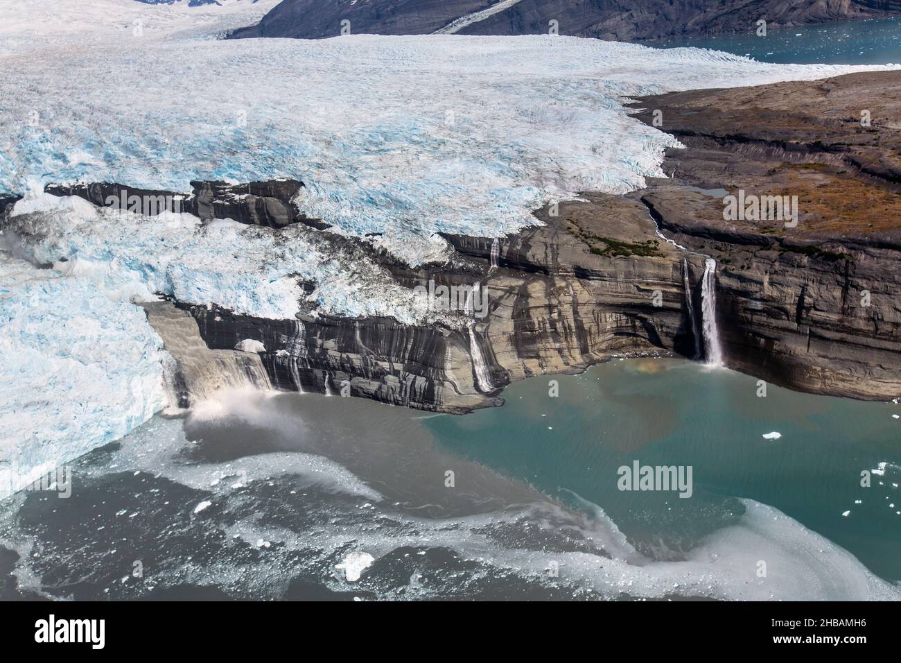 Le acque che fuoriuscendo dal Ghiacciaio Guyot al suo capolinea in Icy Bay (Wrangell-St. Elias National Park, Alaska) sono nuvolosi con farina glaciale sospesa. La differenza tra il sedimento altamente concentrato nella baia vicino al ghiacciaio e quello dell'acqua più diluita a destra è impressionante. Ghiacciai: Glacier Flour Una versione unica e ottimizzata di un'immagine di NPS Ranger JW Frank; Credit: NPS/Jacob W. Frank Foto Stock