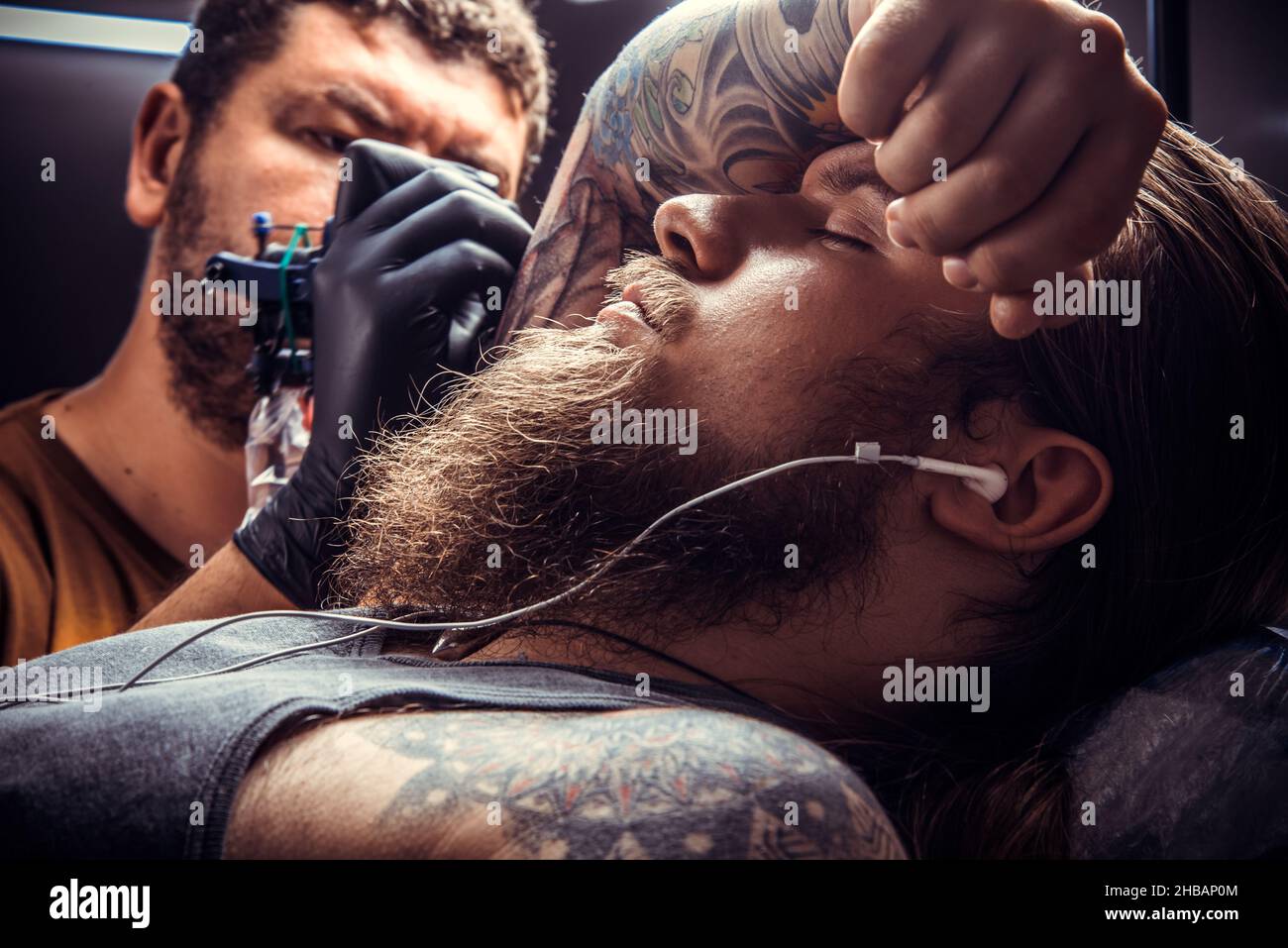 Tatuatore professionale al lavoro in salotto tatuaggio Foto Stock