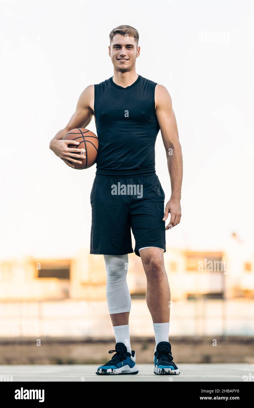 Ritratto verticale di un uomo alto con una pallacanestro all'aperto Foto Stock