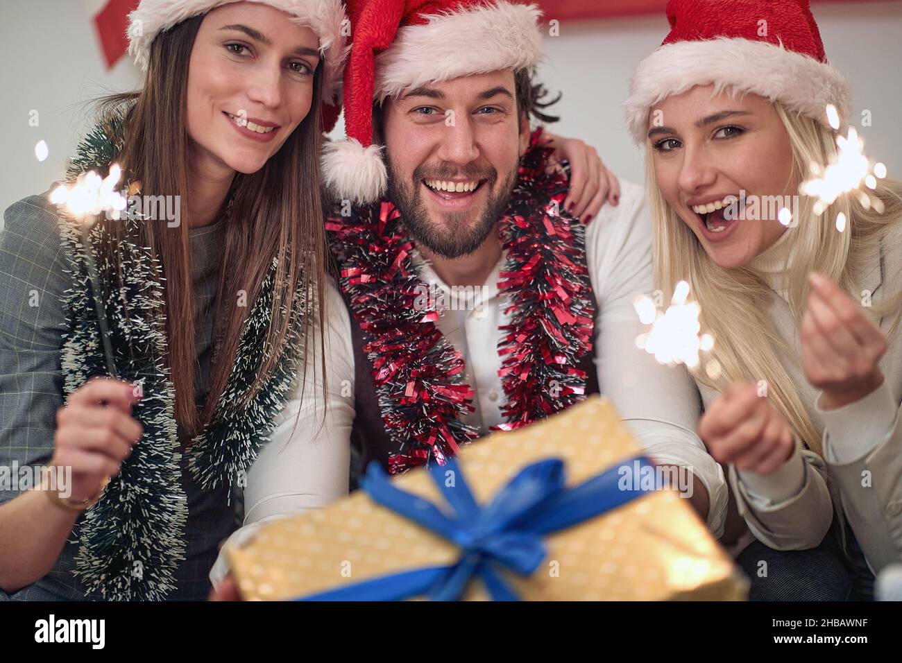 Giovani amici con scintille e regalo godendo in festa il giorno di Natale Foto Stock