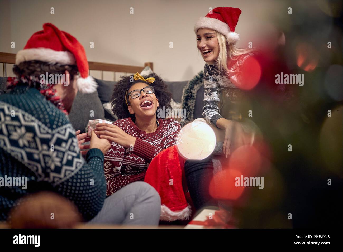 Un gruppo di amici sta avendo un buon tempo mentre ripartiscono i regali durante la festa di Capodanno in un'atmosfera festosa a casa. Natale, Capodanno, vacanze, p. Foto Stock