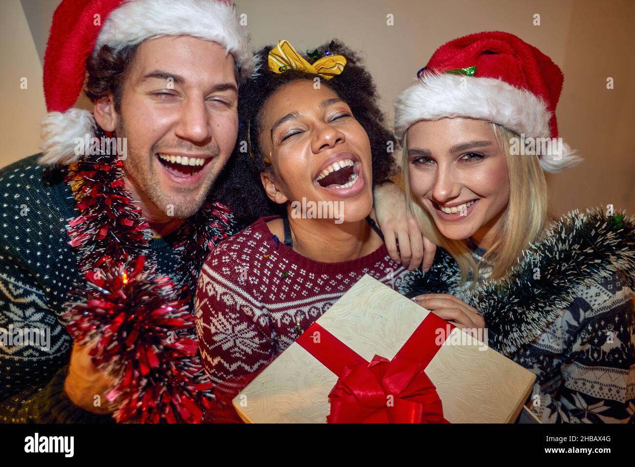 Primo piano di un gruppo di amici allegri che hanno un buon tempo mentre si posa per una foto durante una festa di Capodanno in un'atmosfera festosa a casa. Natale Foto Stock