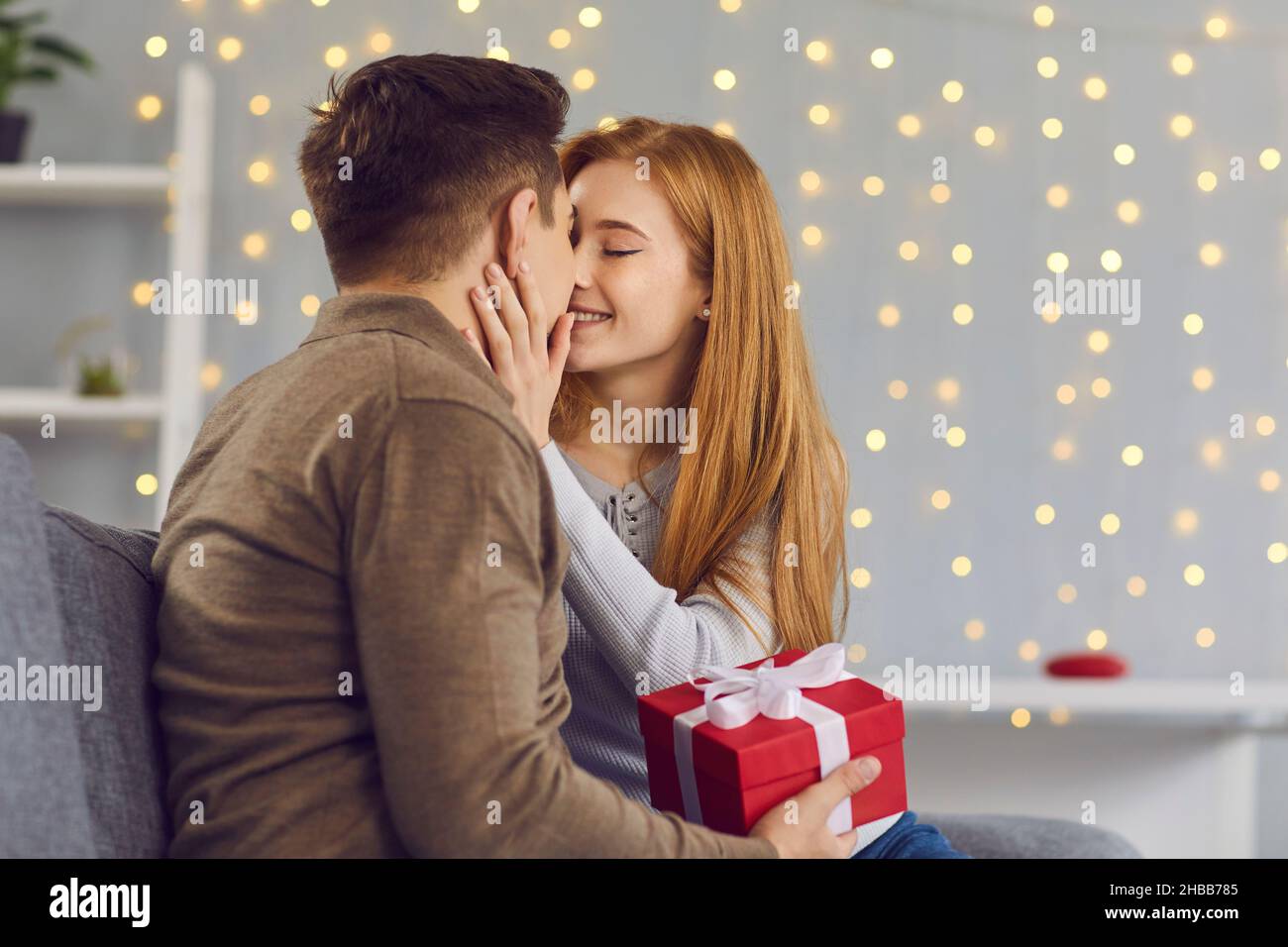 Giovane coppia felice in amore baciare durante dare regali e celebrare le vacanze Foto Stock
