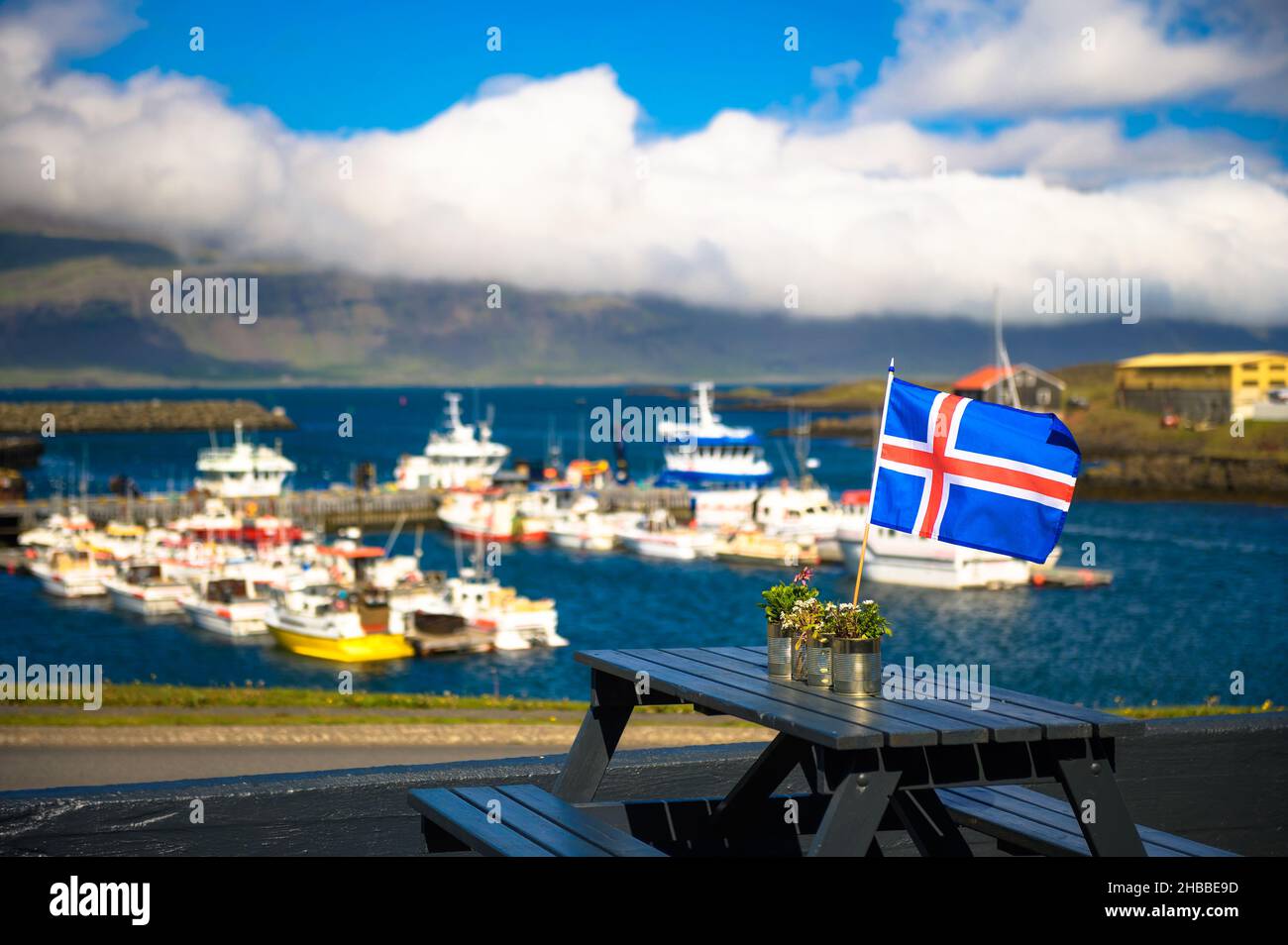 Bandiera d'Islanda posto su un tavolo da ristorante con un porto sullo sfondo Foto Stock