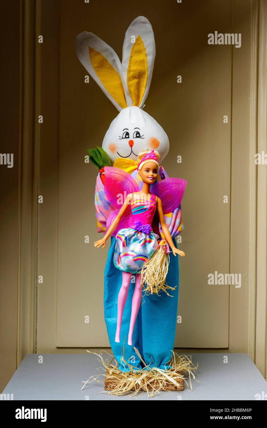 Coniglio felice imbottito che tiene una bambola Barbie con ali rosa, Foto Stock