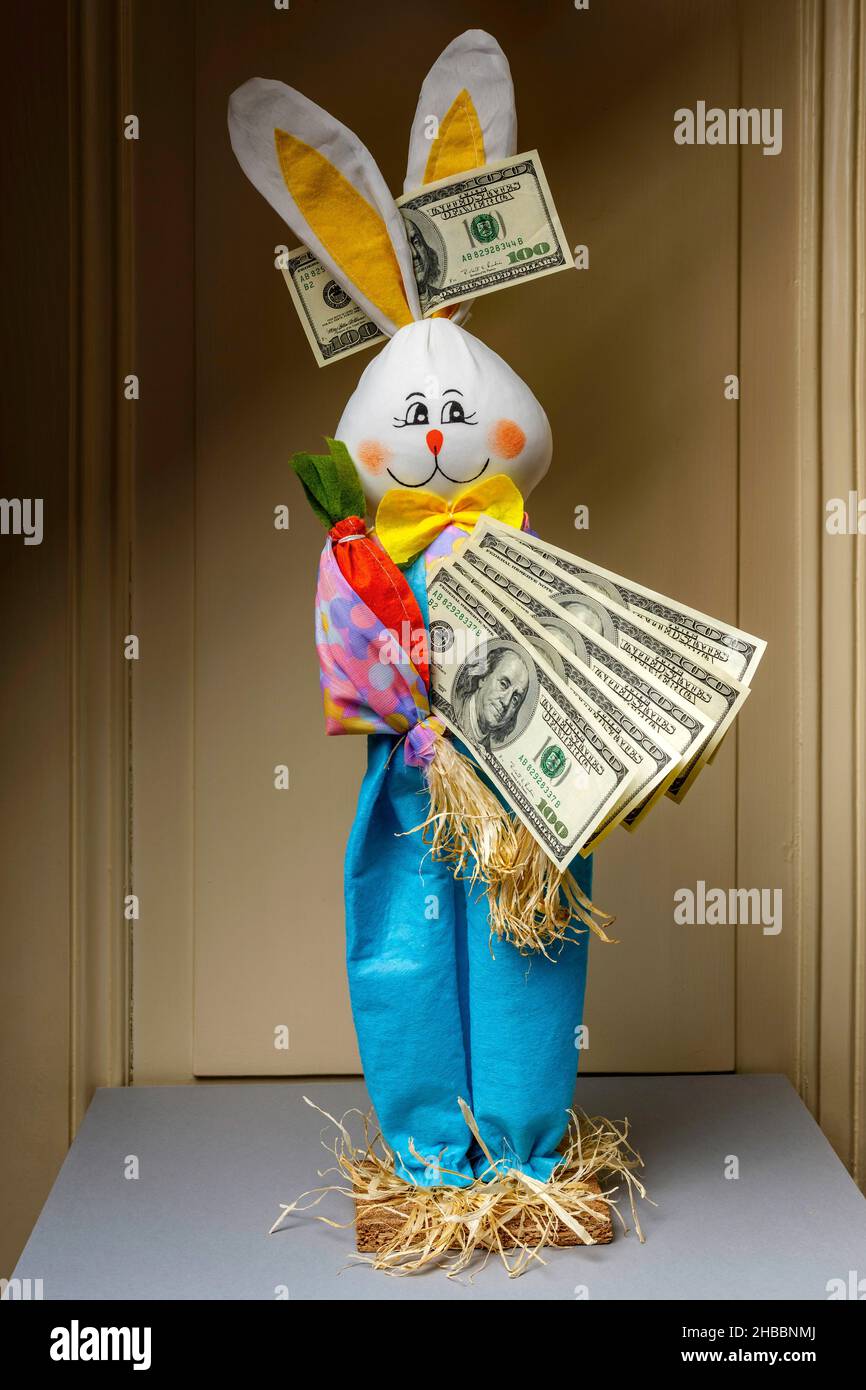 Coniglio felice imbottito che tiene un ventilatore di cento banconote di dollari USA con 1 banconote di un dollaro USA tra le orecchie, Foto Stock