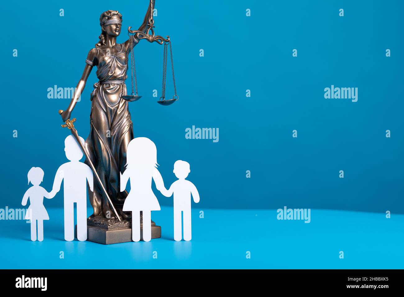 Statua di una donna con scale come simbolo di legge su una superficie blu con silhouette di bambini Foto Stock Statua di una donna con scale come simbolo di legge su una superficie blu con silhouette di bambini Foto Stock