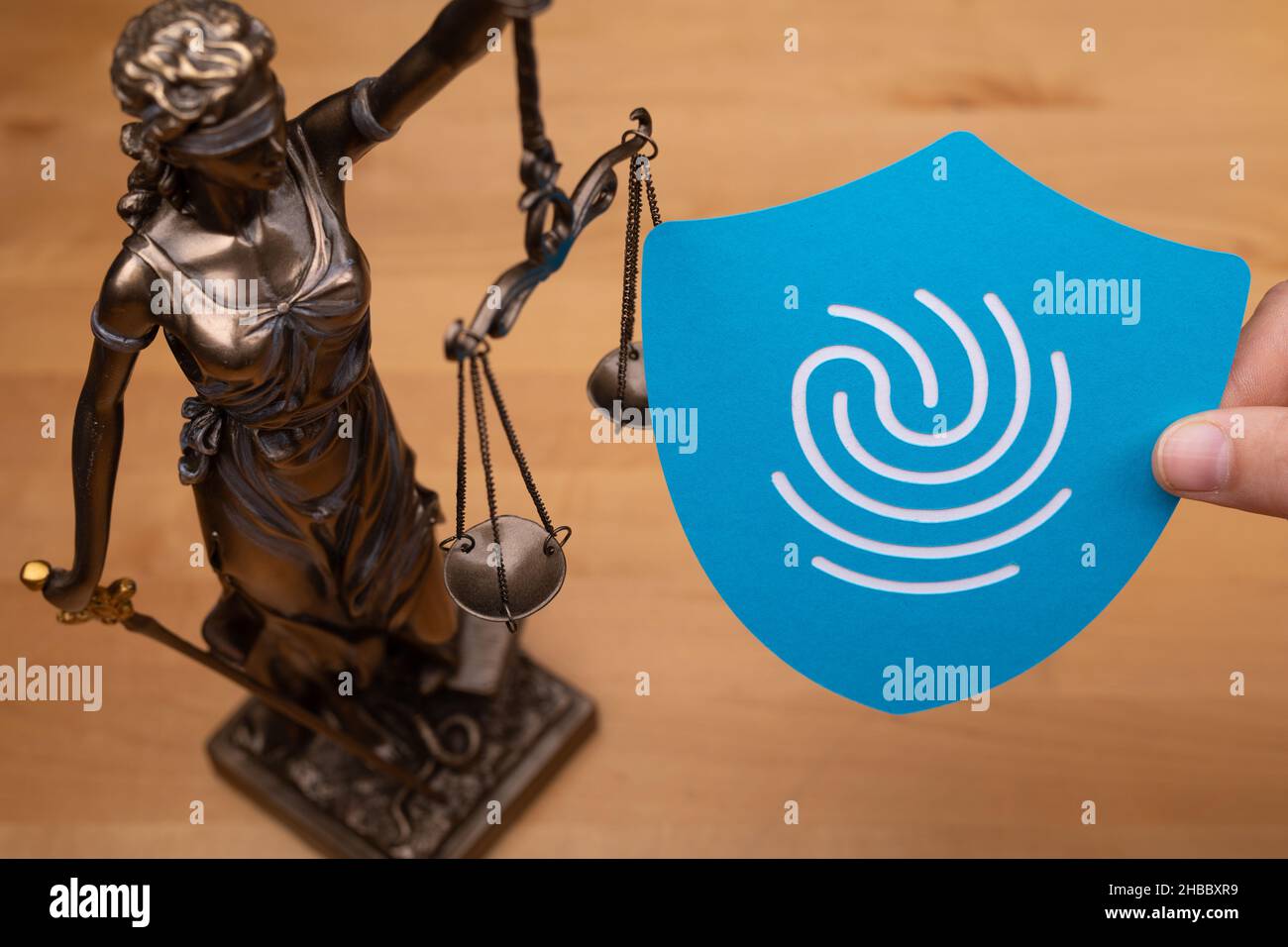Statua di una donna con le scale come simbolo di legge e un'impronta digitale su una superficie di legno Foto Stock Statua di una donna con le scale come simbolo di legge e un'impronta digitale su una superficie di legno Foto Stock