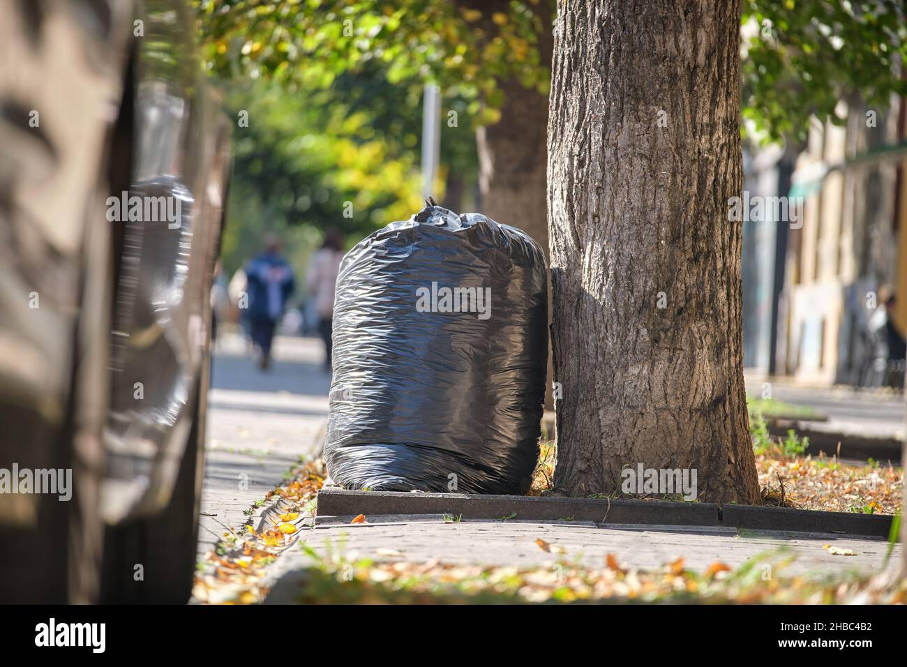 Mucchio di sacchi di rifiuti neri pieno di lettiera sinistra per pick up sul lato della strada. Concetto di smaltimento rifiuti. Foto Stock