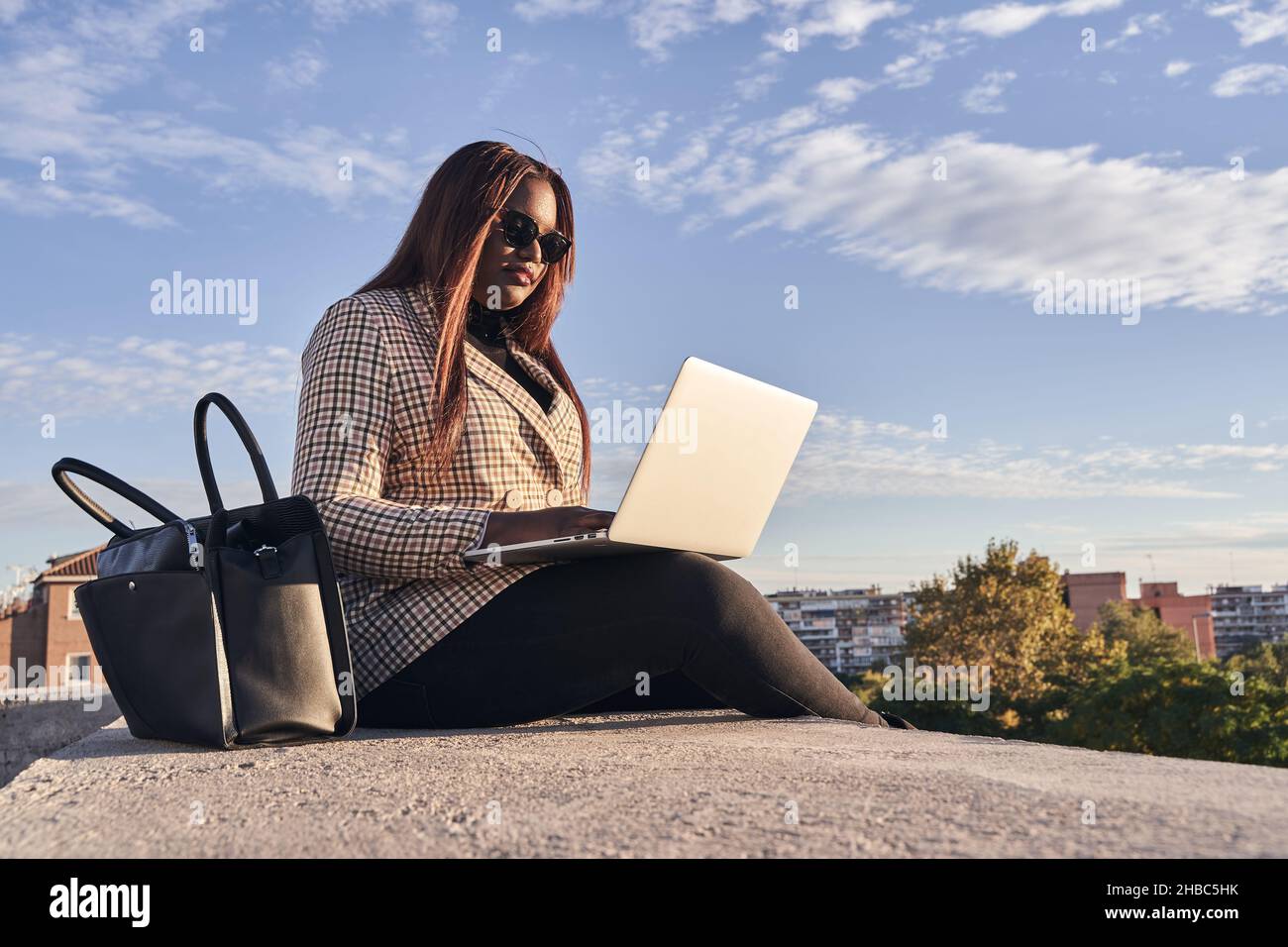 Giovane donna d'affari afroamericana che lavora sul computer outdoor.Young ragazza che lavora sul laptop al tramonto o all'alba, giorno di lavoro. Foto Stock