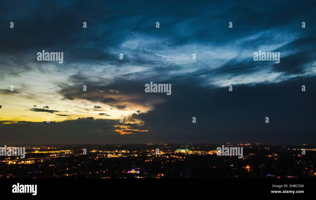 Una vista panoramica delle luci notturne che si accendono mentre il sole tramonta con le nuvole Foto Stock