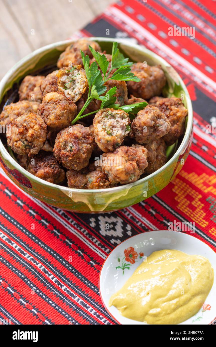palle di carne fritte in un recipiente di argilla su un panno tradizionale Foto Stock