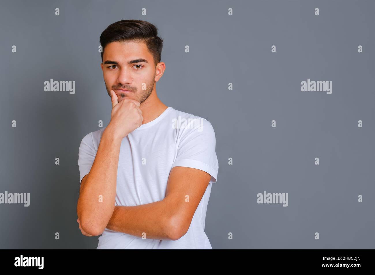 Un ragazzo bello e pensivo che tocca il mento non rasato Foto Stock