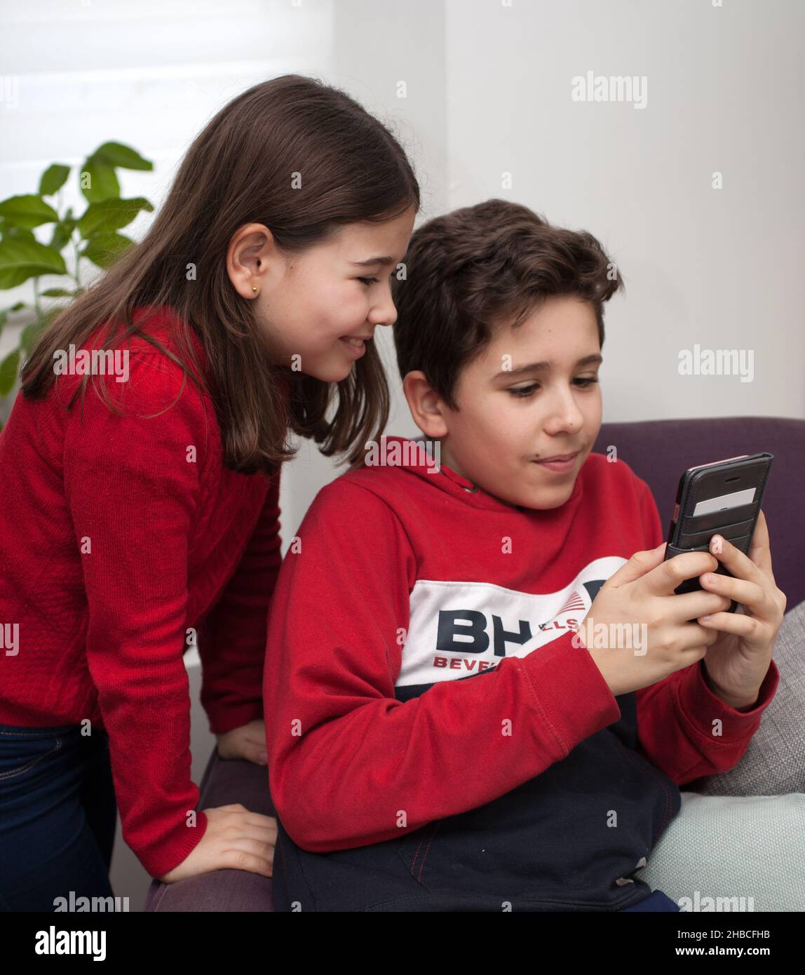 Un fratello e una sorella che guardano un telefono cellulare Foto Stock