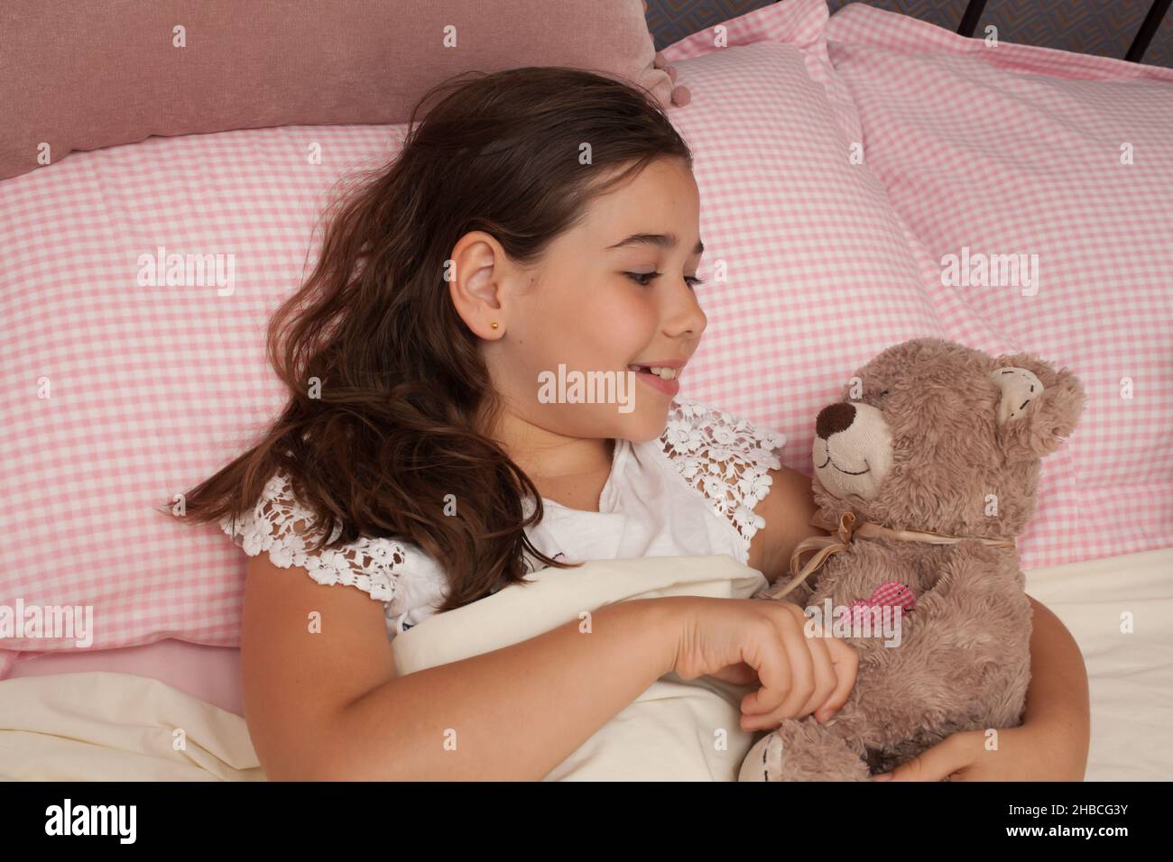 Una ragazza nel suo letto con il suo orsacchiotto, preso il 13 agosto a Wool, Dorset, Regno Unito Foto Stock