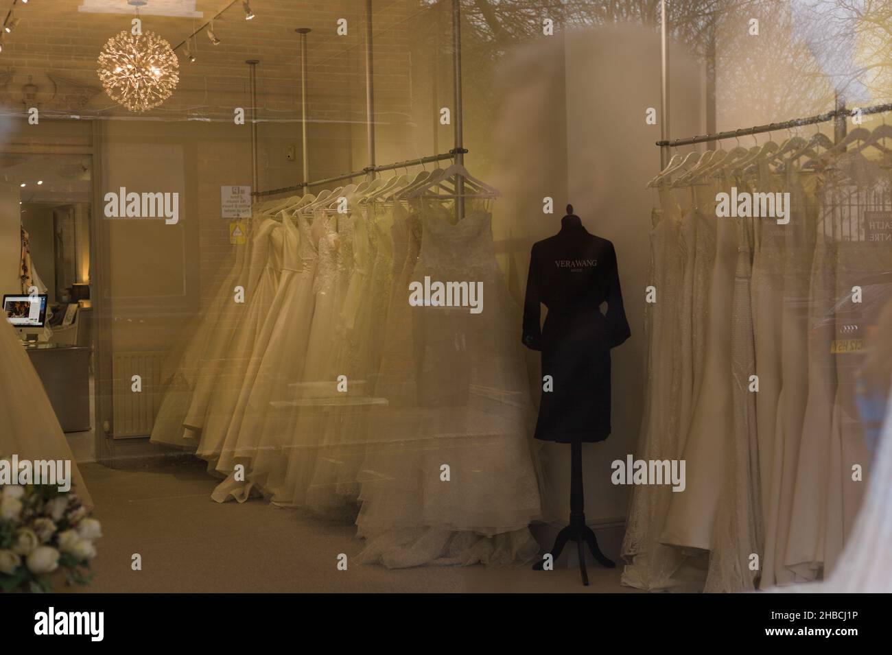 Regno Unito. Inverno 2021. Linee di vestiti di cerimonia nuziale che si aggettano su una rotaia attraverso una finestra del deposito britannico di cerimonia nuziale Foto Stock