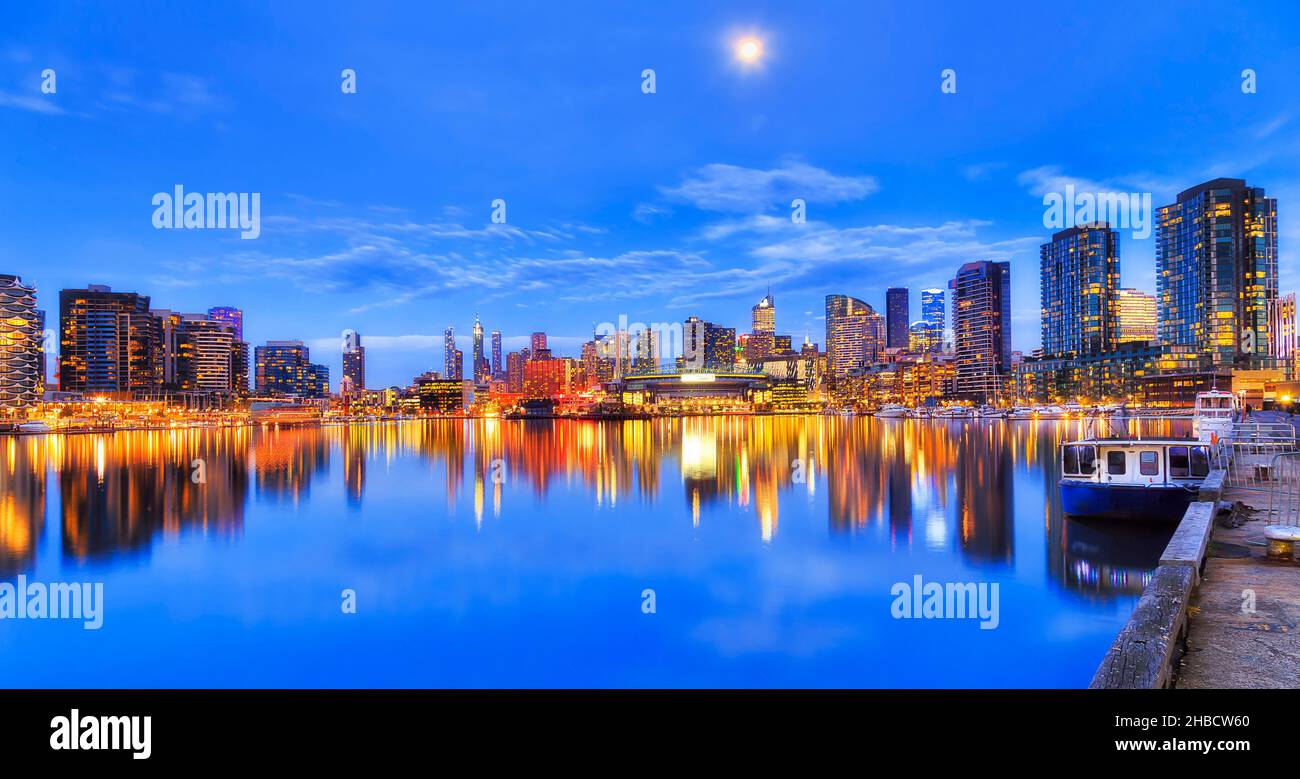 Ampio e tranquillo riflesso di Docklands moderno paesaggio urbano nella città di Melbourne al susnet con luci luminose. Foto Stock