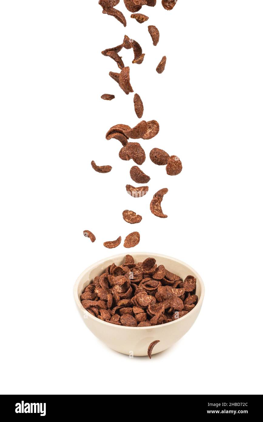 Fiocchi di mais al cioccolato che cadono nella ciotola bianca isolata su bianco. Movimento. CopySpace. Foto Stock