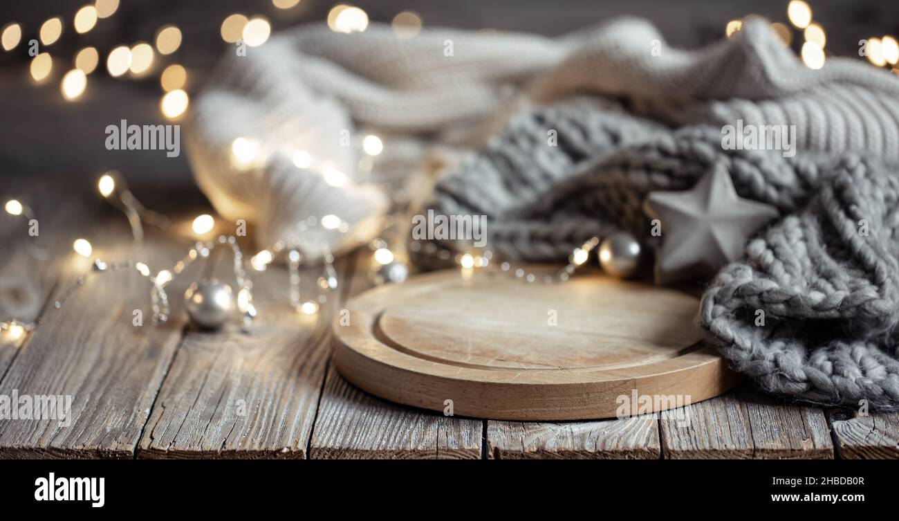 Sfondo accogliente con elemento in maglia su un elemento in legno e luci bokeh. Foto Stock