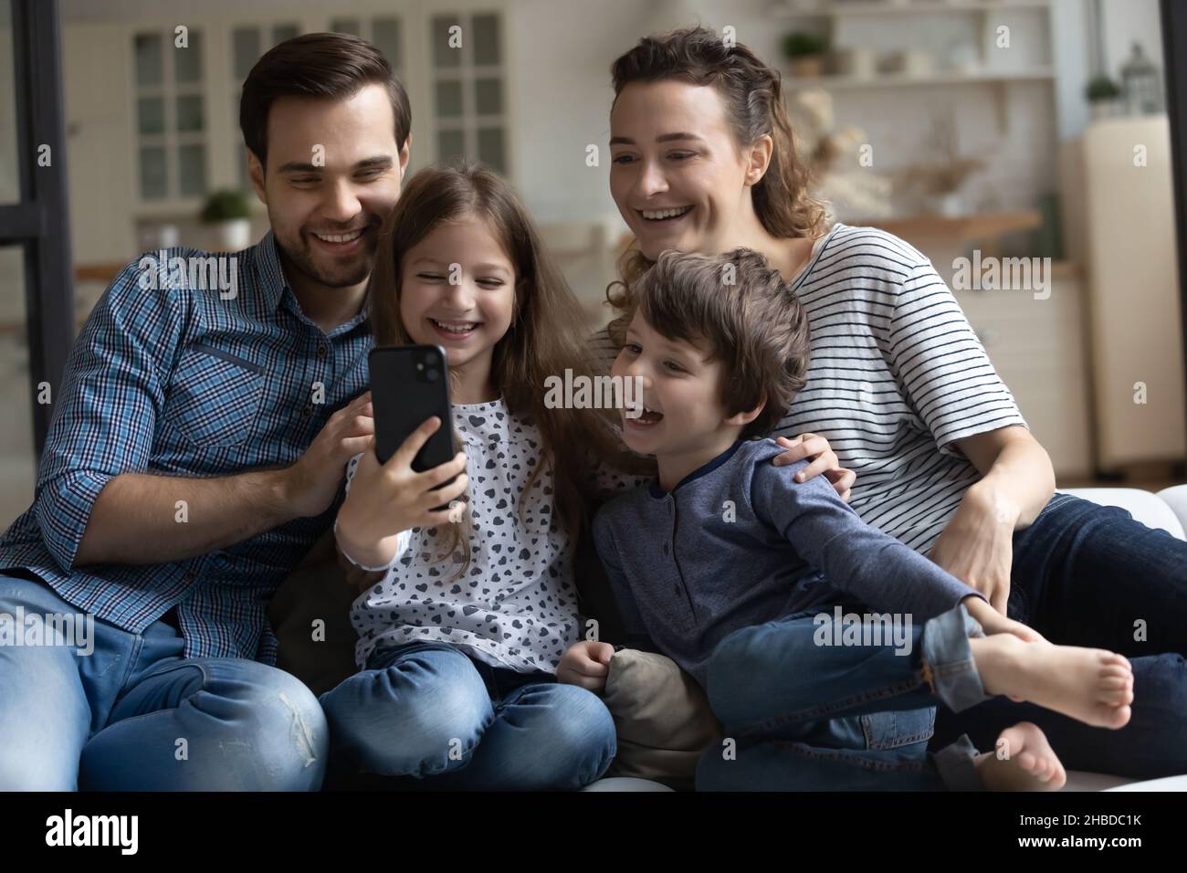 Felici i genitori e i due bambini che si divertono con lo smartphone Foto Stock