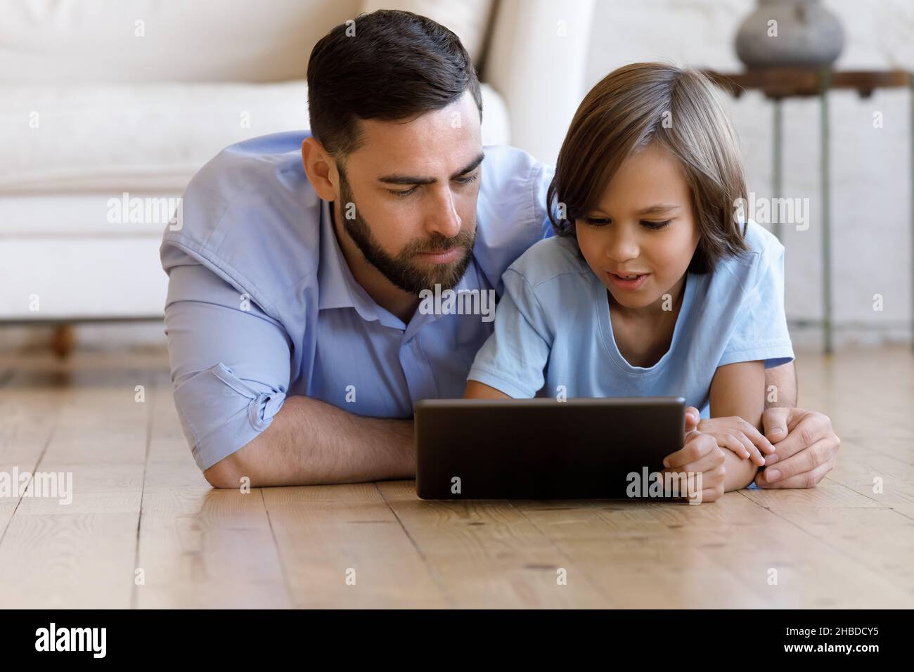 Felice padre giovane e adolescente sob utilizzando il tablet digitale. Foto Stock
