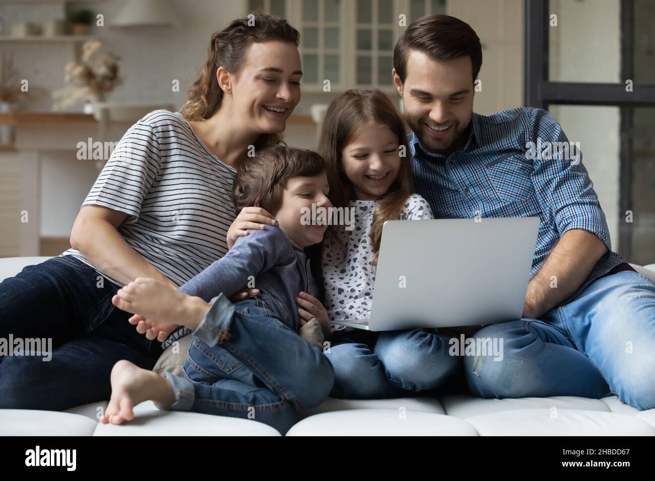 Una famiglia felice con due bambini che usano un computer portatile a casa insieme Foto Stock