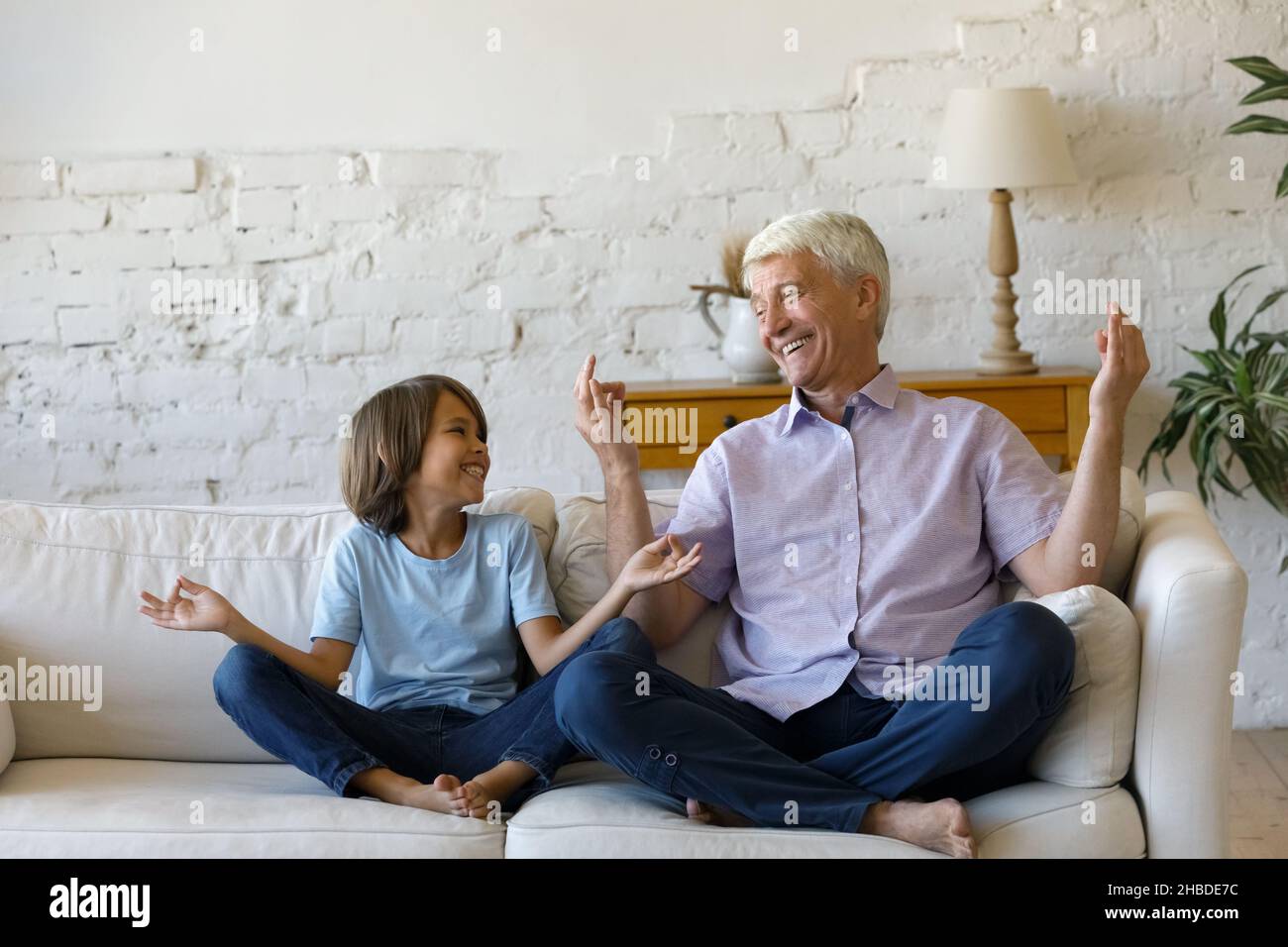 Ragazzo felice di premedere che pratica yoga con il nonno vecchio. Foto Stock