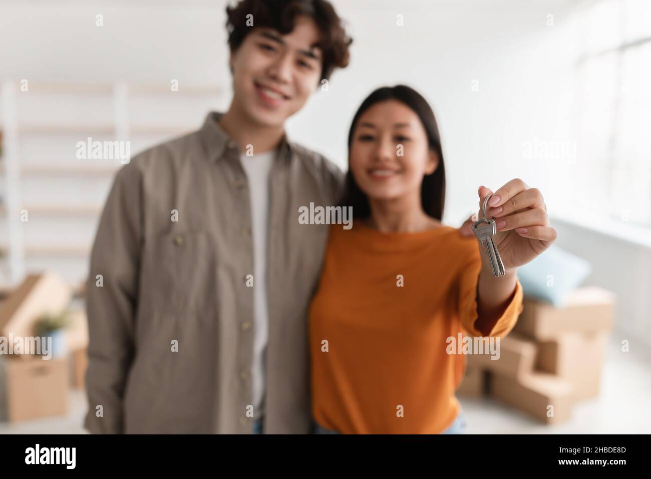 Felice coppia asiatica che mostra la chiave della casa a macchina fotografica, che si sposta al proprio appartamento, fuoco selettivo Foto Stock