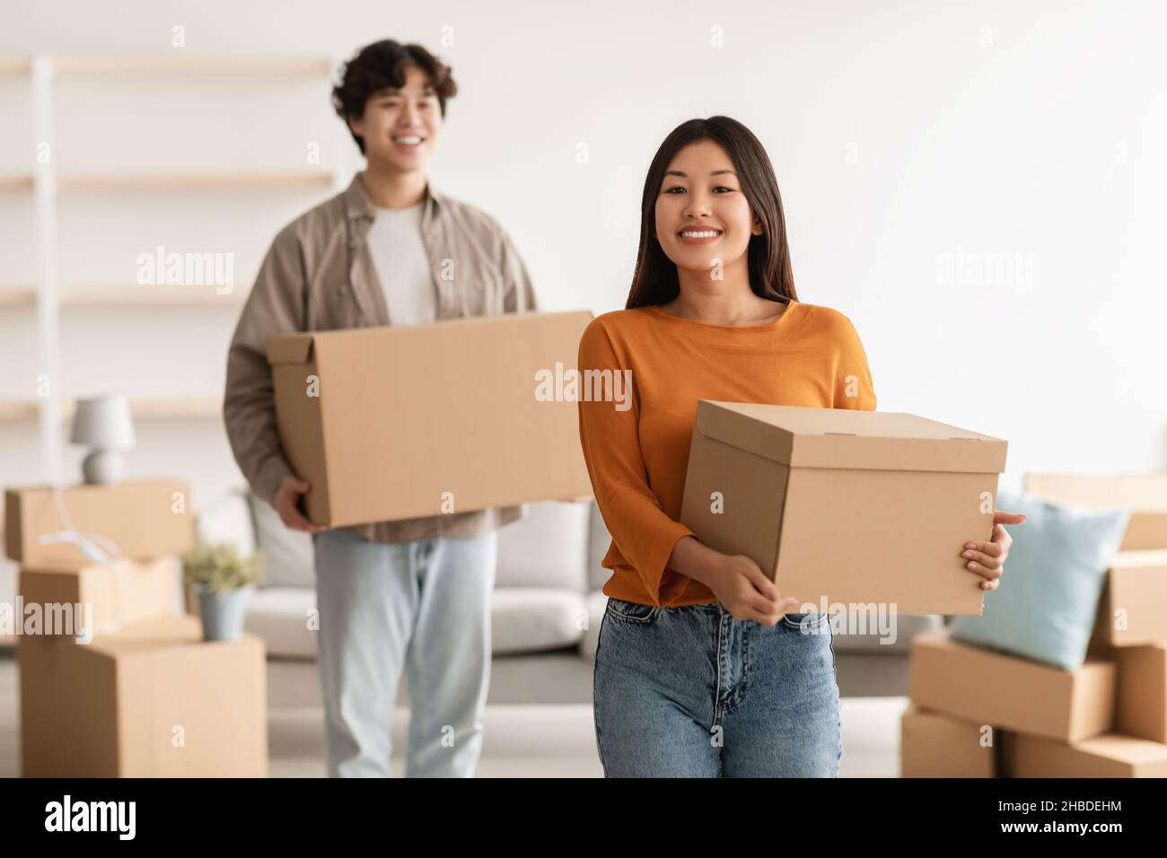 Passare a un nuovo concetto di casa. Donna asiatica felice e il suo ragazzo con scatole di cartone che si trasferiscono a casa propria Foto Stock