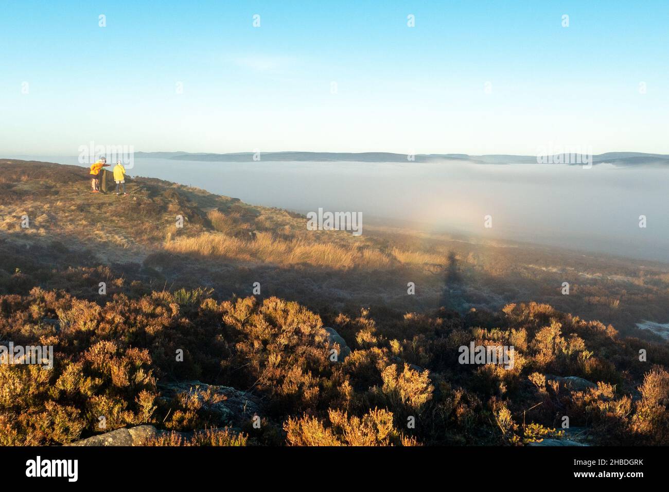 Ilkley, Yorkshire UK, 19 Dicembre 2021 - Fellrunner godere di guardare l'inversione del cloud e raro fenomeno di broccen specter tempo su Ilkley Moor. Credit: Rebecca Cole/Alamy Live News Foto Stock