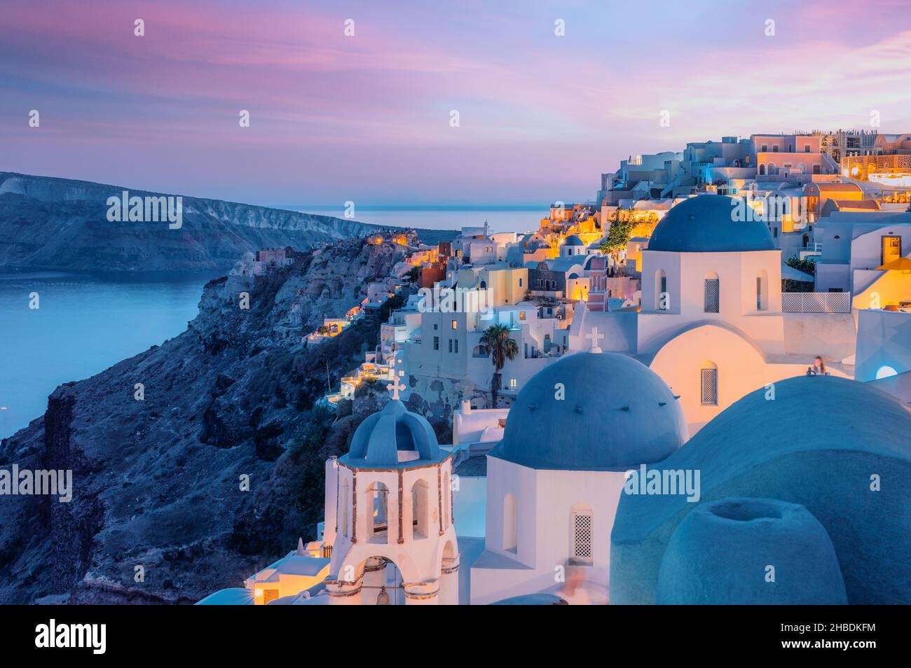 Tramonto colorato e drammatico con luci notturne nella città mediterranea di Oia, Santorini, Grecia, Europa Foto Stock