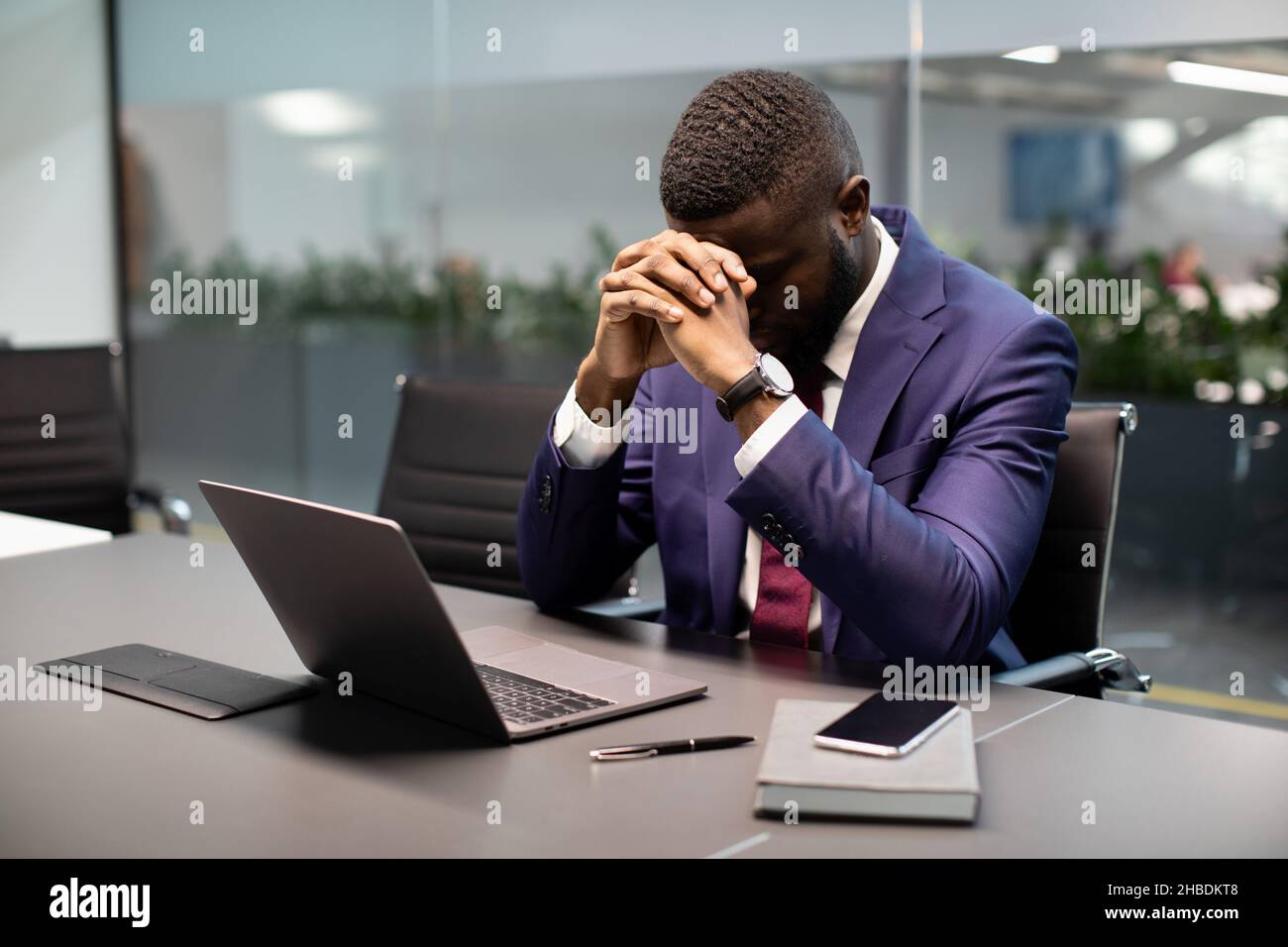 Uomo d'affari nero frustrato seduto davanti al laptop Foto Stock