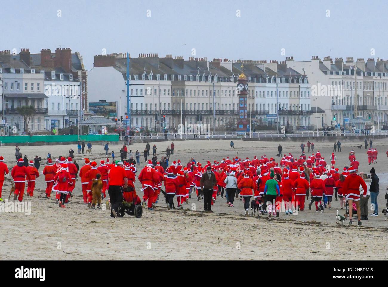 Weymouth, Dorset, Regno Unito. 19th dicembre 2021. Centinaia di corridori vestiti come Babbo Natale prendono parte all'annuale The Chase the Pudding pre-chistmas correre sulla spiaggia di Weymouth nel Dorset. L'evento annuale sta raccogliendo fondi per la carità Mackaness fiducia. Corridori sulla spiaggia. Picture Credit: Graham Hunt/Alamy Live News Foto Stock